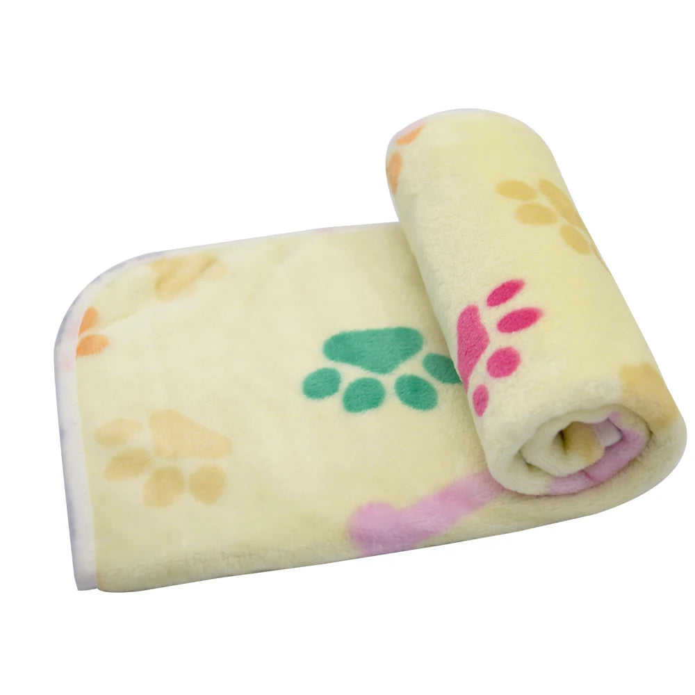 A rolled yellow dog blanket with pink and green paw prints.