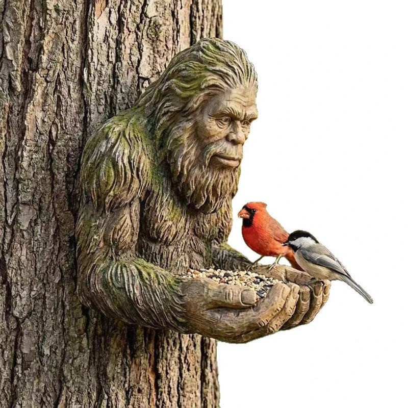 A resin sculpture of a tree hugger with a bird feeder perched on his hand.