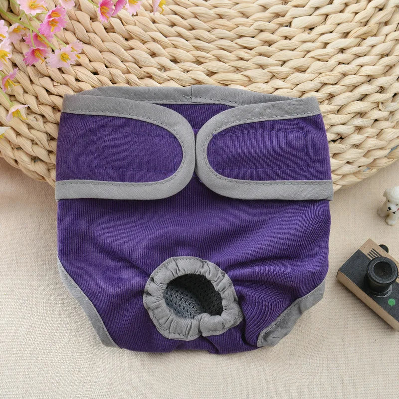 Purple and gray reusable dog diapers lying on a woven mat with pink flowers.