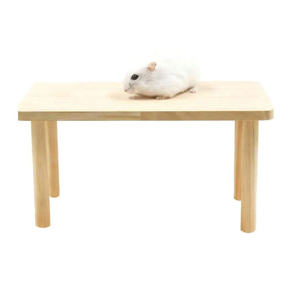 A white hamster is resting on a light wooden platform.