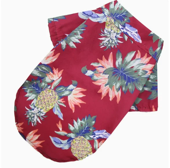 A red short-sleeved shirt with a tropical floral print featuring blue, green, and pink leaves and pineapple motifs.