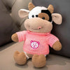 A soft plush toy of a cow with black and white markings, pink clothing, and brown accents.