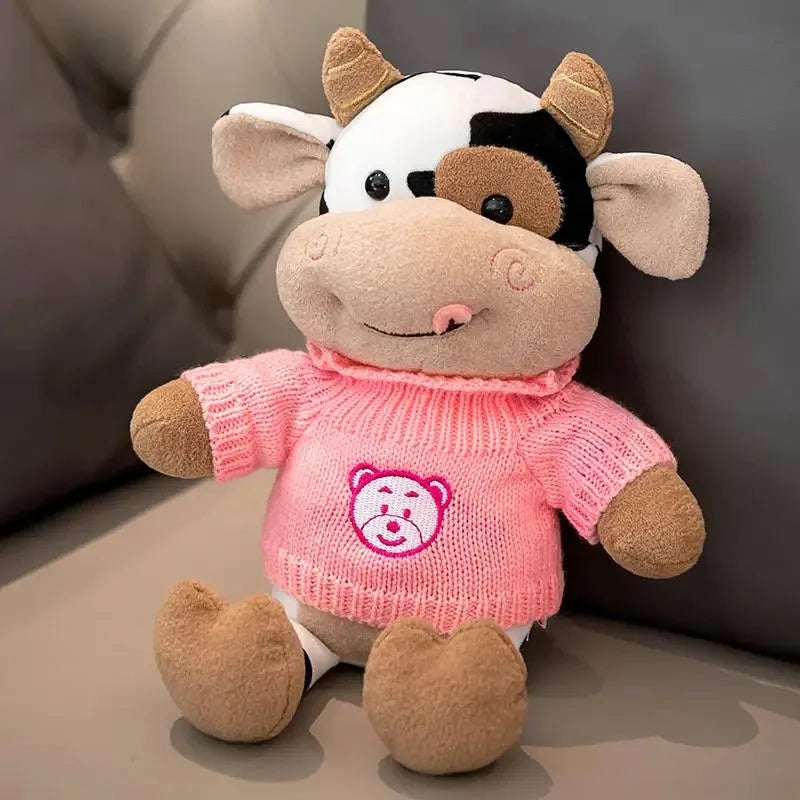 A soft plush toy of a cow with black and white markings, pink clothing, and brown accents.