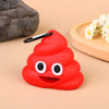 Dispensador de silicona rojo brillante con forma de emoji de popó sonriente y clip negro, sobre una superficie de madera clar