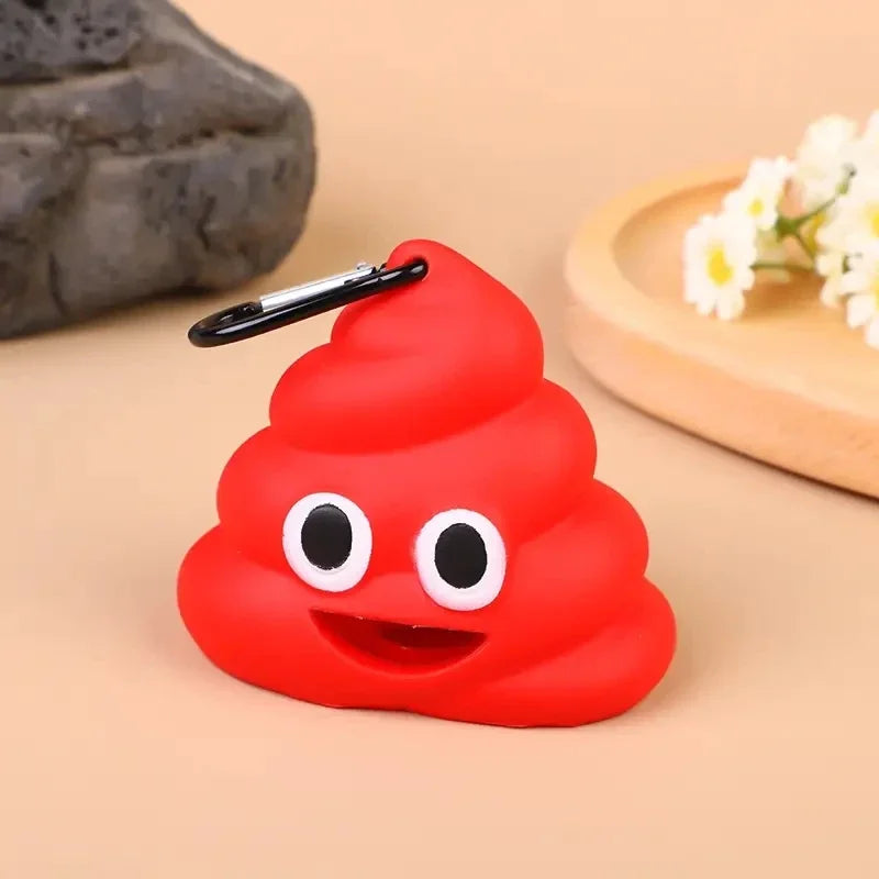 Dispensador de silicona rojo brillante con forma de emoji de popó sonriente y clip negro, sobre una superficie de madera clar