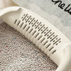 A white high-sided cat litter box with anti-splash design is shown from a side angle on a patterned surface.