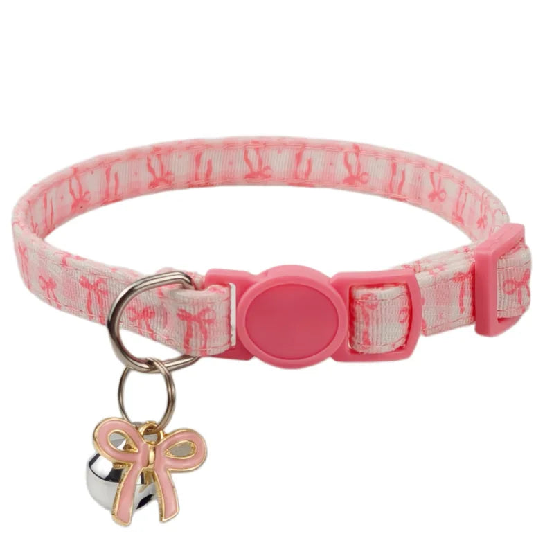 A pink aesthetic cat collar with a matching pink patterned strap and a small bow pendant.