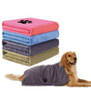 A stack of pink, blue, and gray microfiber dog towels next to a brown dog lying down with a purple towel.