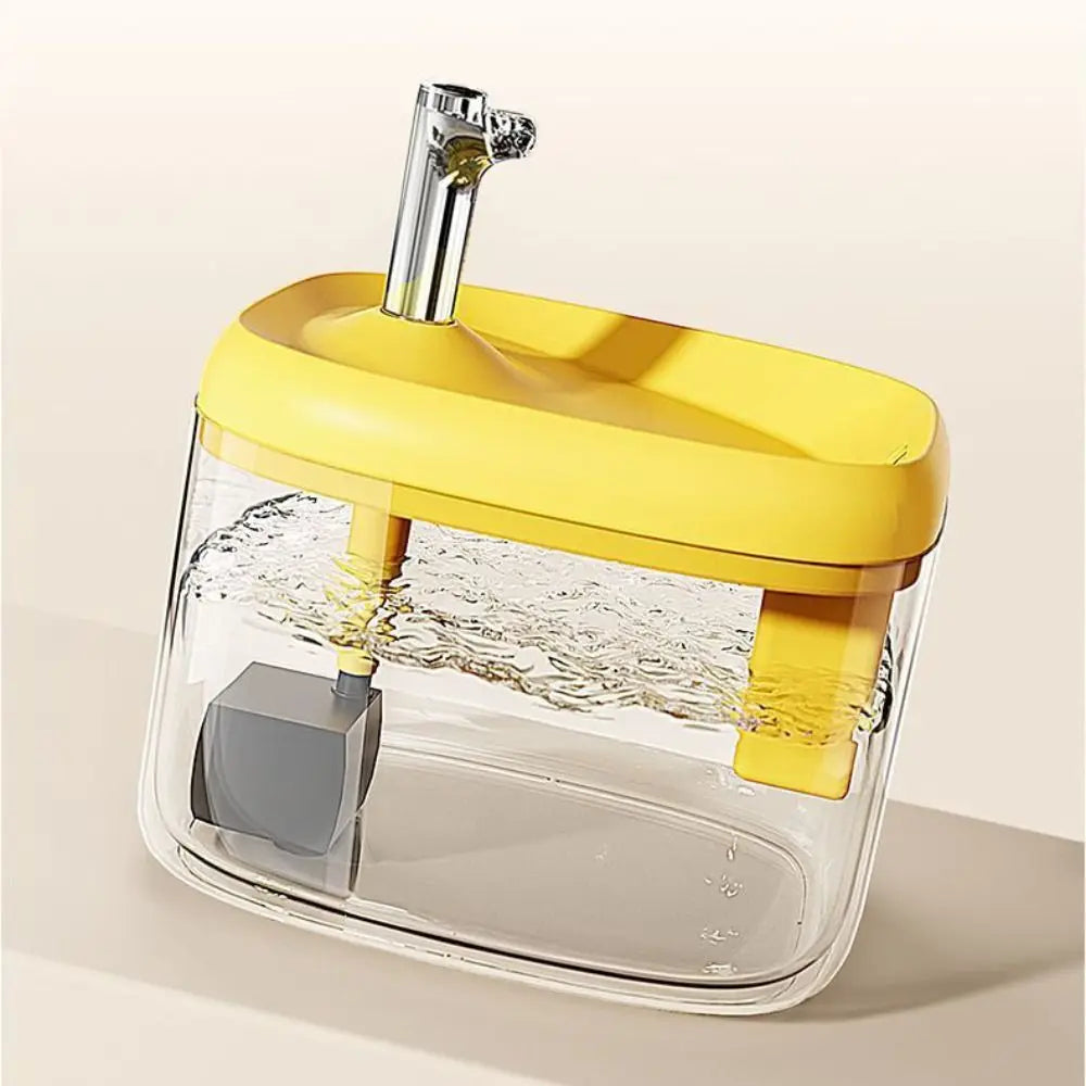 A clear glass cat drinking fountain with a yellow base and a silver spout, showing water flowing.