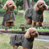 Un chien brun clair et duveteux portant un peignoir gris absorbant pour se laver dehors.