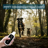 A hand holds a remote control device used for 3000FT remote control signal control in a wooded outdoor setting with dogs.
