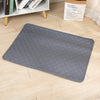 A gray reusable washable pet training mat lying on a light wooden floor.