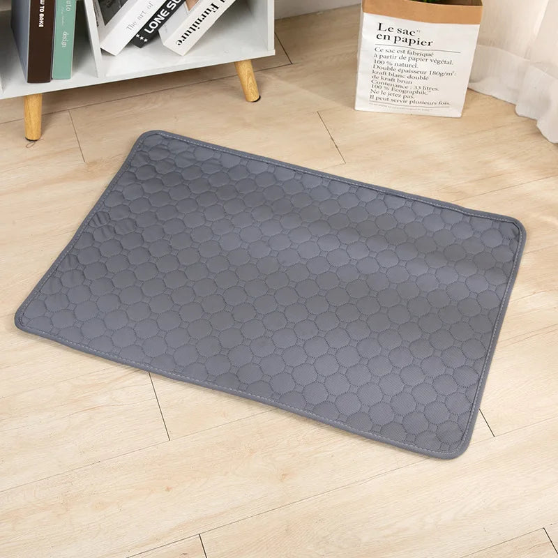 A gray reusable washable pet training mat lying on a light wooden floor.