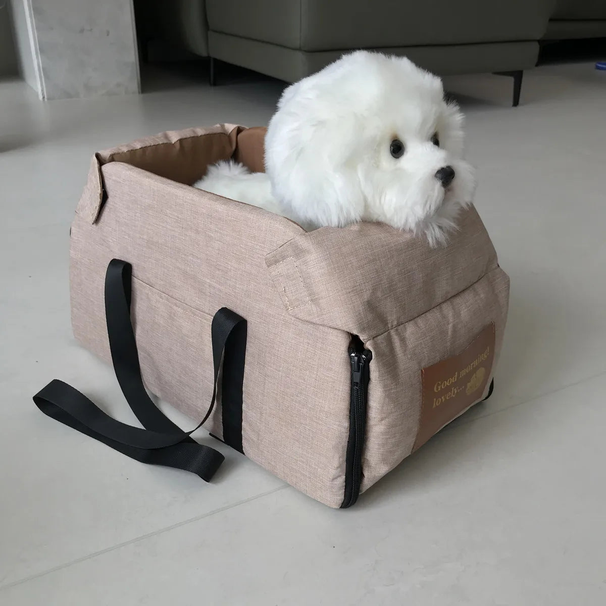 Ein flauschiger weißer Hund ruht in einem beigen Transportbehälter mit Reißverschluss und schwarzem Gurt.