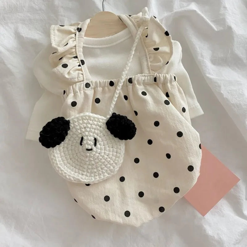 A white summer dot pet dress for a small dog with ruffled trim and a large embroidered face detail.