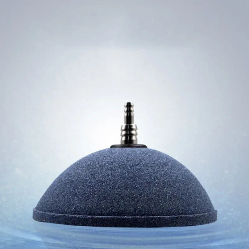 A dark blue, dome-shaped aquarium air stone disc floating in clear water.