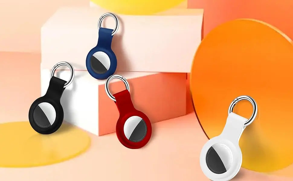 Various silicone airtag protective covers in black, blue, red, and white with metal keychains displayed on a light background