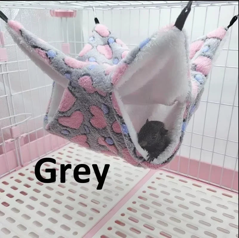A grey cozy double-layer fleece hammock for small pets is shown inside a white cage.