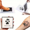 A hand holds an inkless pet paw print kit showing a black paw print and the name Savannah on a white background.