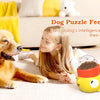 A young girl is interacting with a yellow dog puzzle feeder toy for dogs on a light-colored rug.