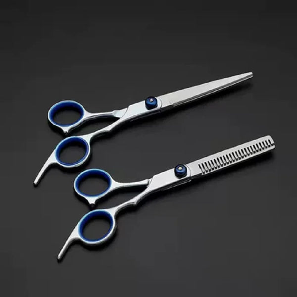 A pair of professional stainless steel hairdressing scissors with blue accents resting on a dark surface.