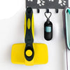 A yellow multi-functional pet grooming comb and scratcher set with a black handle and a hanging accessory.