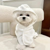 A white fluffy dog wearing an absorbent quick-dry bathrobe, sitting on a white surface.