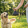 A person is holding a dog leash attached to a black mesh bag of dog waste bags while a golden retriever looks up.