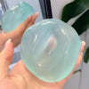 Eine Hand hält eine durchsichtige, hellblaue Stressball-Kugel mit glatten, abgerundeten Oberflächen.