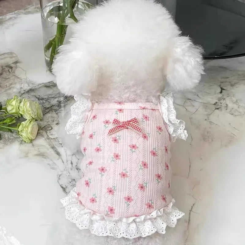 A pink floral print vest for a dog or cat with white fluffy trim and lace detailing.