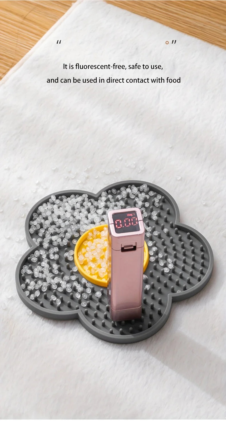 A pink silicone lick mat with a yellow treat is placed on a gray silicone feeding dish.