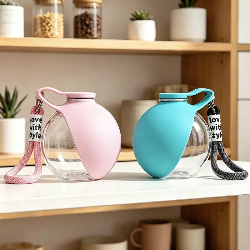 A pink glass water bottle with a teal silicone cap and lanyard is displayed on a wooden shelf.