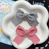 A pair of red plaid fabric bows displayed on a white plate.