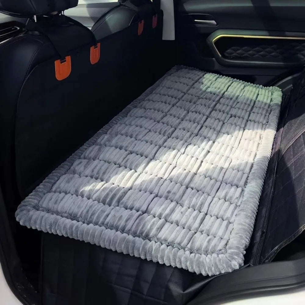 A gray plaid flannel pet seat protector and car mat placed in the back seat of a vehicle.