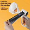 A hand is holding a white external garbage bag storage box with a black bag, demonstrating its use for waste disposal.