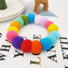 A colorful pet collar and bow tie set featuring fuzzy pom-poms in shades of green, yellow, pink, purple, and blue.