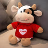 A red and white cow plush toy with brown horns and a smiling face.