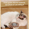 A white and gray kitten is lying next to a silicone pet toy ball on a wooden floor.