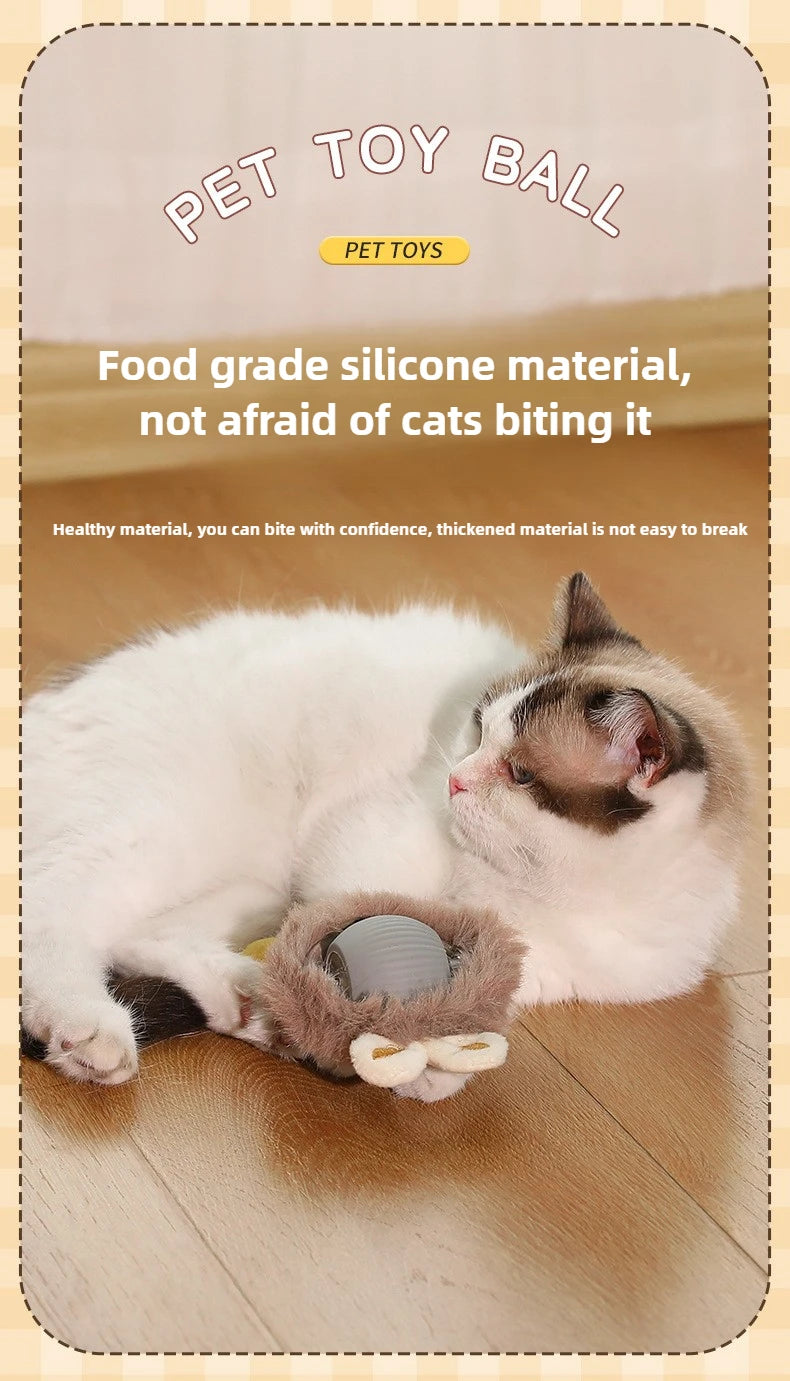 A white and gray kitten is lying next to a silicone pet toy ball on a wooden floor.