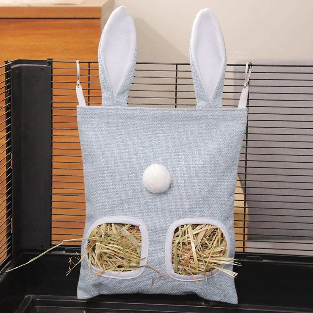 Un sac de foin bleu clair avec deux ouvertures ovales est exposé dans un distributeur pour animaux noir.