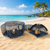 A black mesh portable pet playhouse and cage is set up on a sandy beach with a cat and a rabbit nearby.