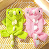 A pair of fuzzy pink and lime green fleece dog hoodies with animal ears lying on a yellow striped fabric.