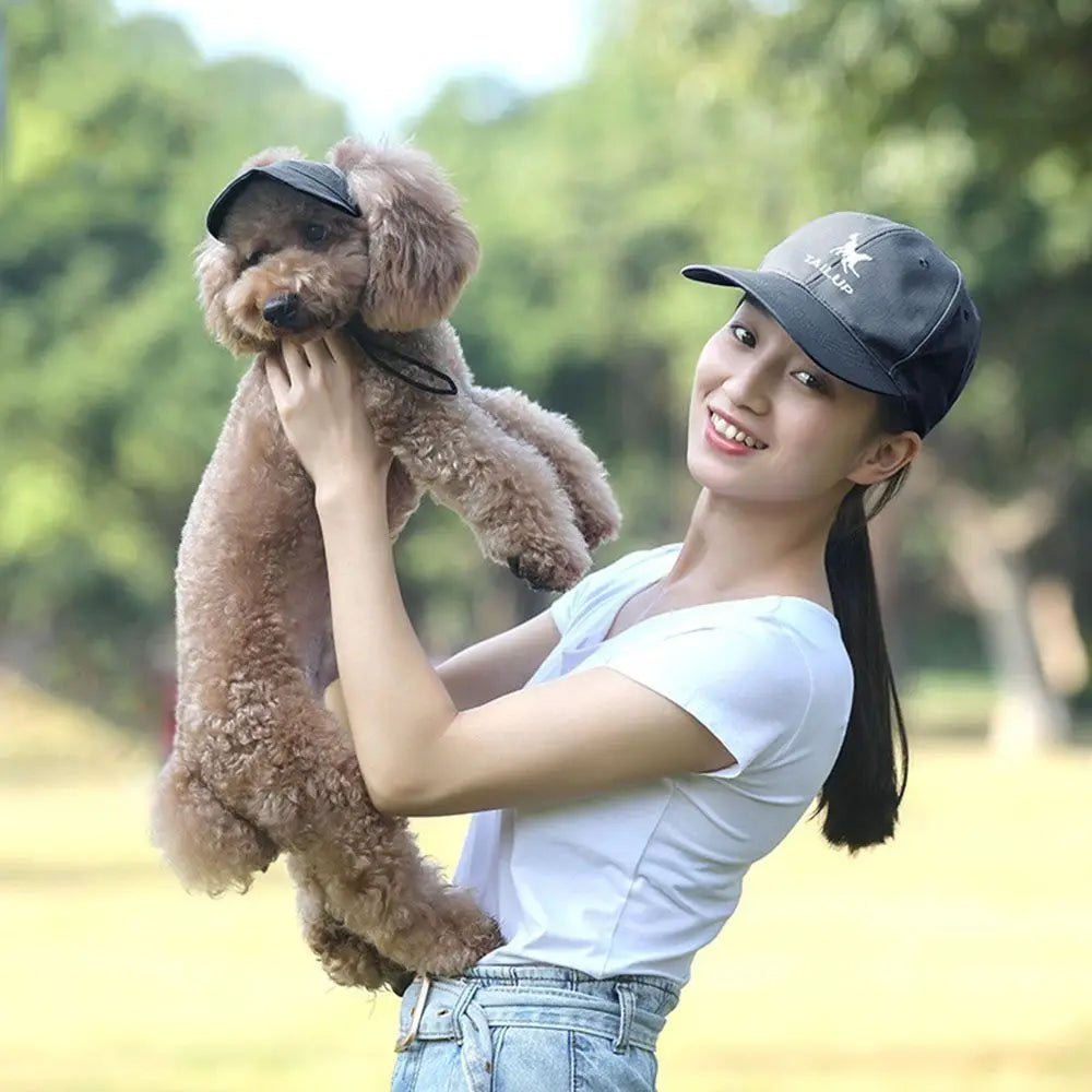 Una joven con gorra de béisbol sostiene a un perro marrón peludo.