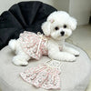 A white fluffy dog wearing a pink floral princess style anti-shedding dress.