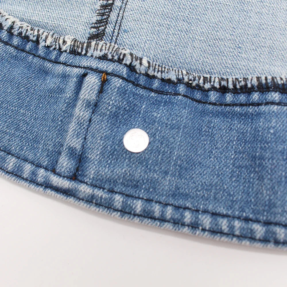 Close-up of a classic blue denim dog jacket showing the fabric texture and a silver D-ring attachment.