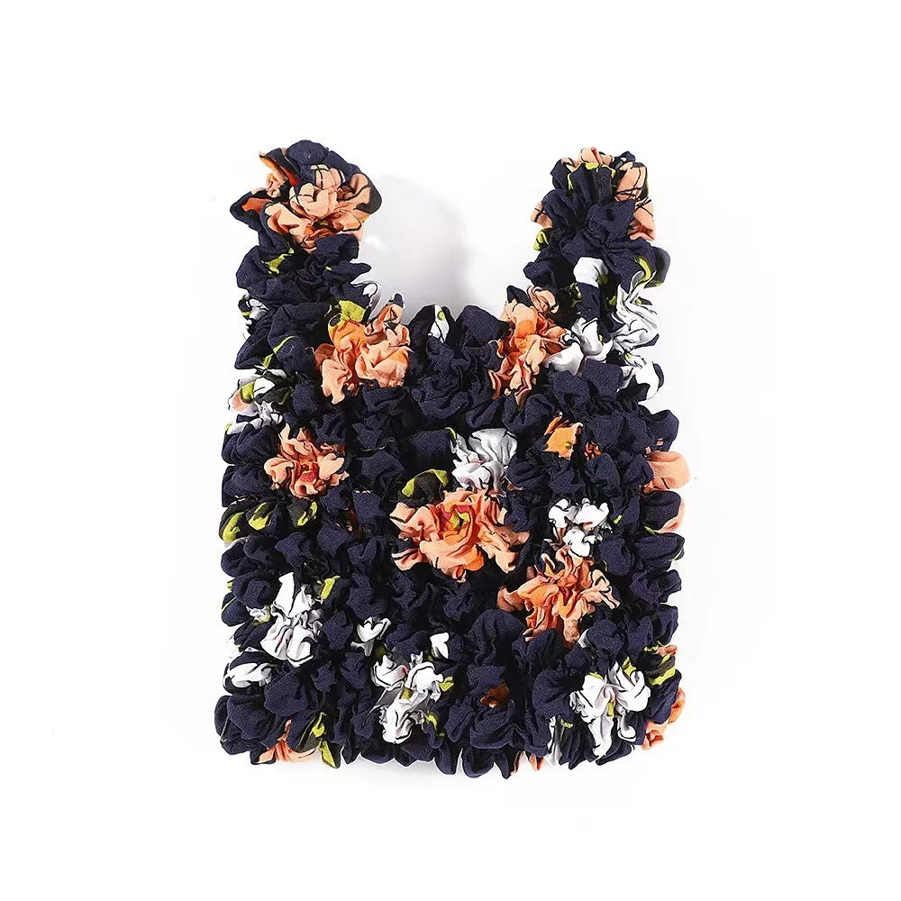 A reusable foldable bubble shopping bag made of dark fabric adorned with orange and white floral fabric flowers.