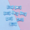 Several light blue bone-shaped hair clips are displayed on a pink and blue background.