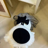 A black lace bow accessory with a white fluffy collar and a dark velvet round patch.