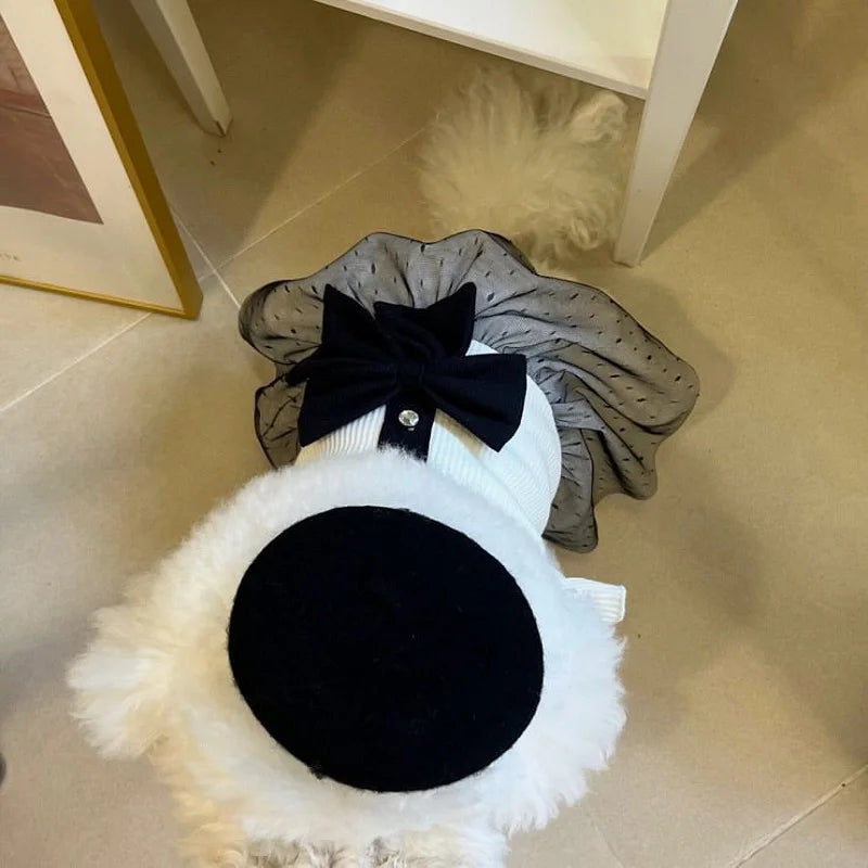 A black lace bow accessory with a white fluffy collar and a dark velvet round patch.