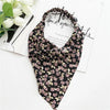 A black triangle scarf featuring a floral paisley pattern in shades of pink and green, displayed on white paper.